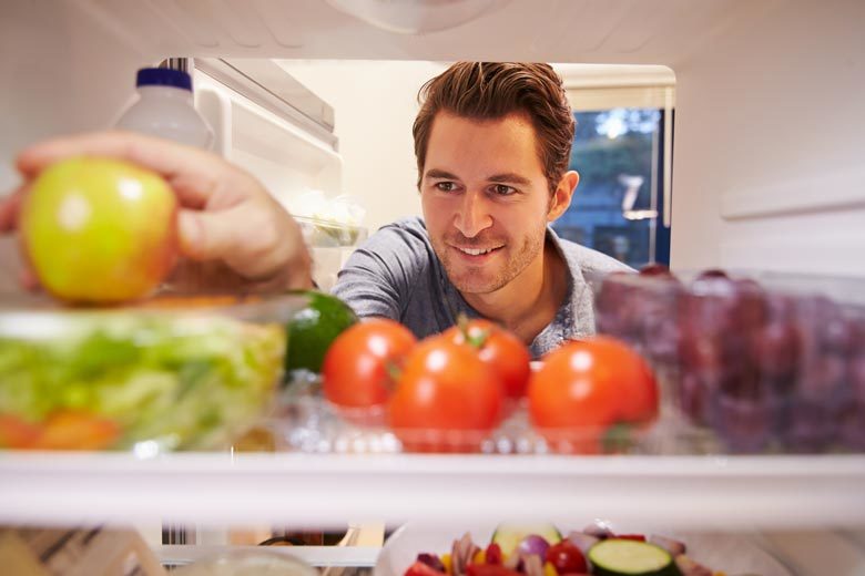 Man reaching into a refrigerator full of healthful food choices