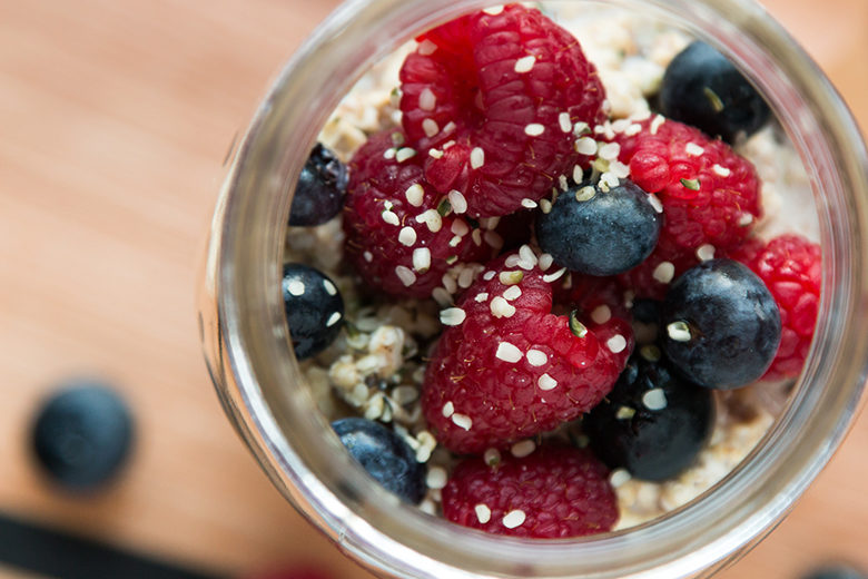Cardamom Overnight Oats in glass jar on countertop with raspberries and blueberries