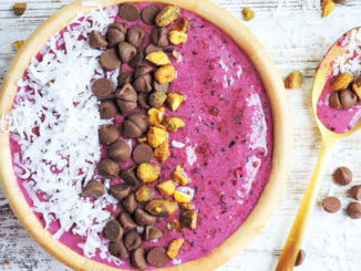 A rich pink Coconut Beet Berry Smoothie Bowl with sections of coconut, chocolate and pistachios as toppings