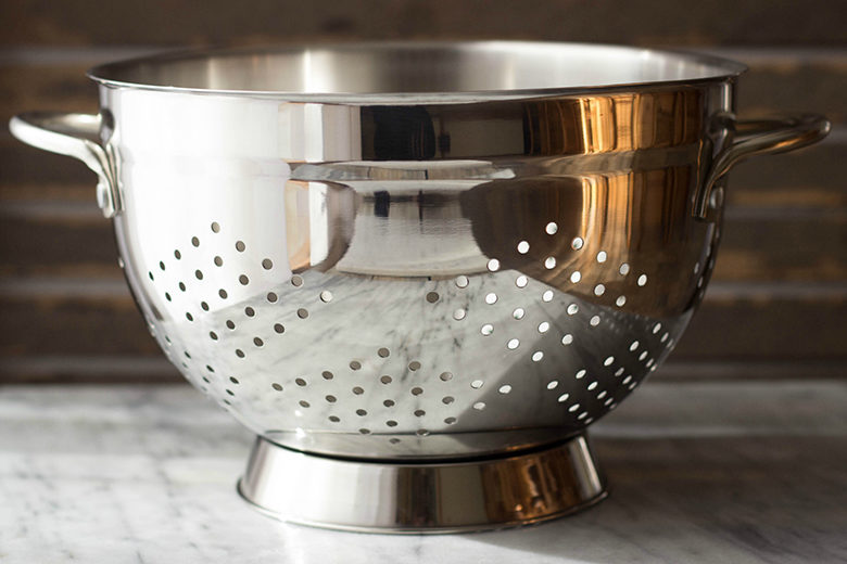 Empty stainless steel colander on marble countertop