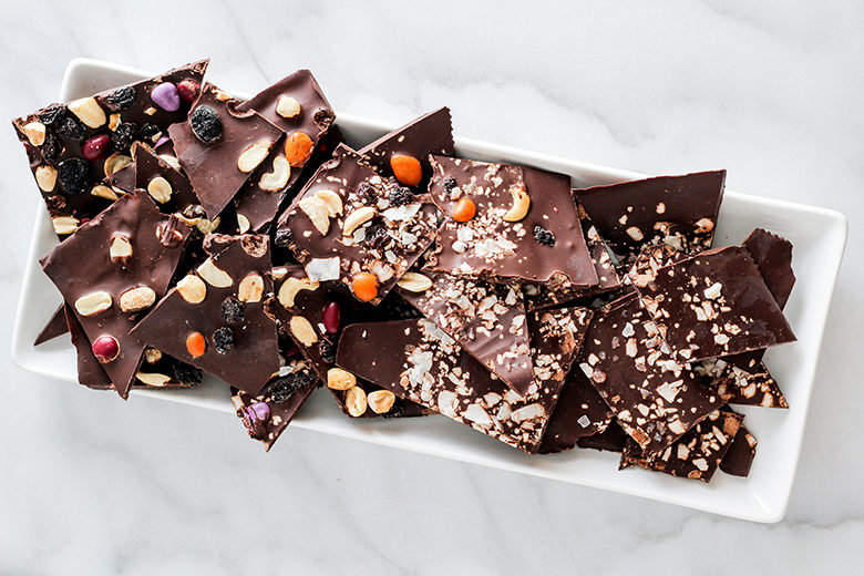 Dark chocolate bark on a white plate with a marble countertop background