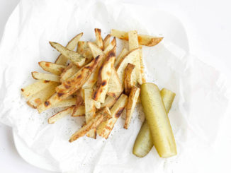 Dill Pickle Baked French Fries next to a pair of dill pickles on white serving paper
