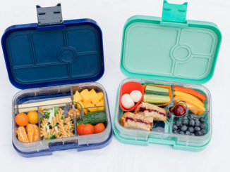 two lunch bento boxes filled with healthy fruits, veggies and more