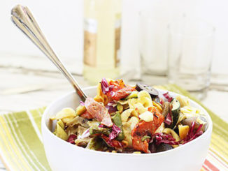 Grilled Vegetable and Tortellini Antipasto Salad in a white bowl with serving spoon