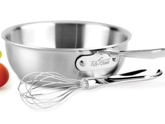 The All Clad Saucier and Whisk on a white background with fruit nearby