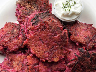 Pink Potato beet latkes with a dollop of sour cream on a plate