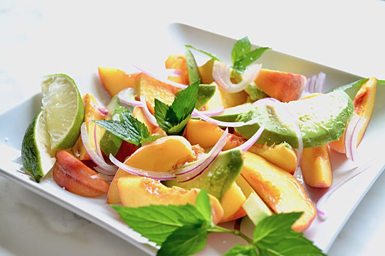 Summer Peach & Avocado Salad with Red Onion and Lime on a square white plate on a white background