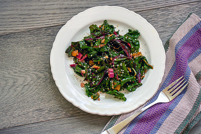 Garlicky Swiss Chard with Sesame Seaweed Sprinkle, on white plate on wooden background with napkin