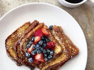 French toast on a white plate with powdered sugar and a medley of berries