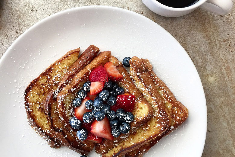 French toast on a white plate with powdered sugar and a medley of berries
