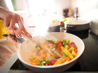 Close up of woman hands mixing food in cooking pan.