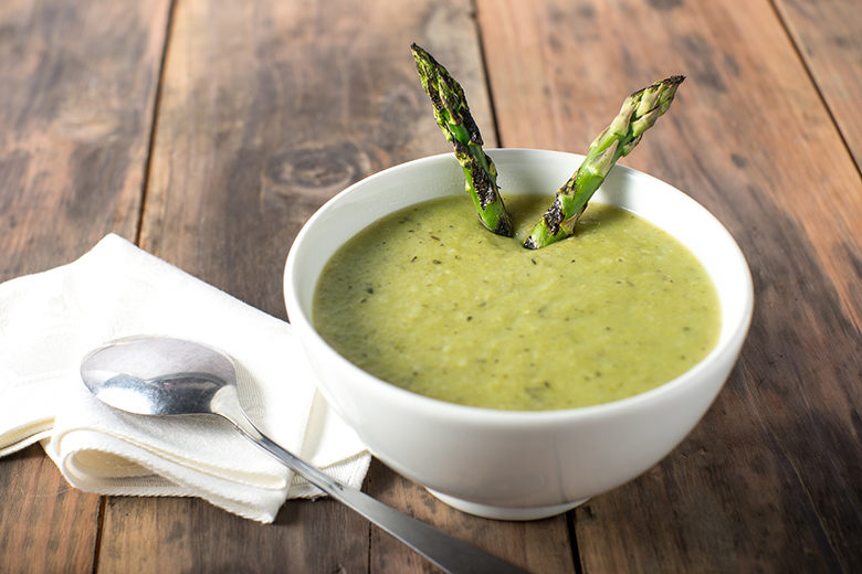 Cream of Asparagus soup in white bowl rustic