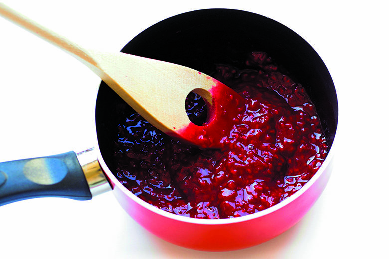 View of homemade raspberry jam in a saucepan.