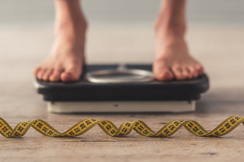Cropped image of woman feet standing on weigh scale