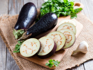 Eggplant slices on cutting board on wooden background