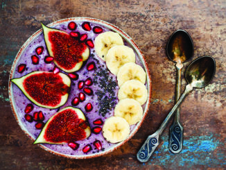 Healthy fall and winter breakfast set. Acai superfoods smoothies bowl with chia seeds, pomegranate, sliced banana, fresh figs and hazelnut butter.