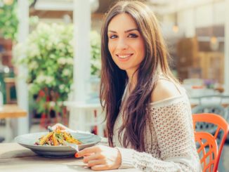 Woman eating salad while sitting at table outdoors