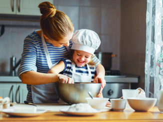 Happy family in kitchen. mother and child preparing dough, bake cookies