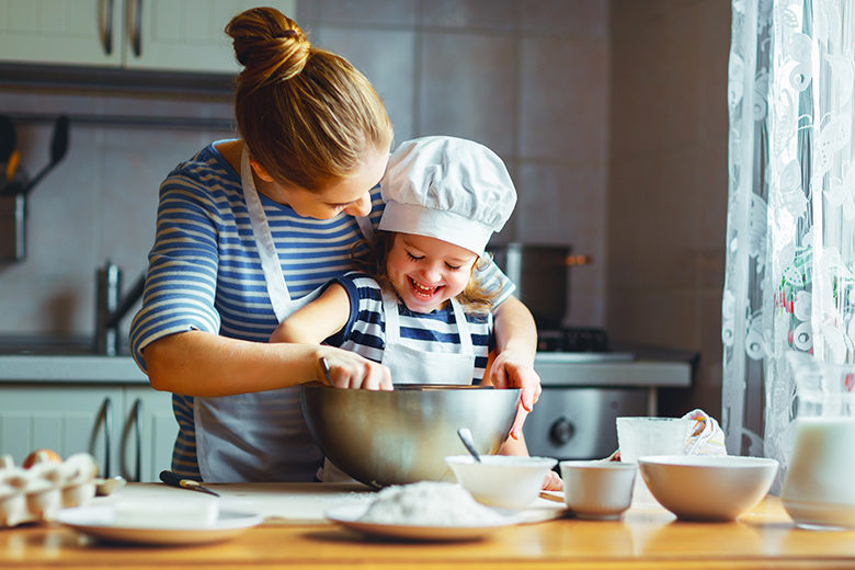 Happy family in kitchen. mother and child preparing dough, bake cookies