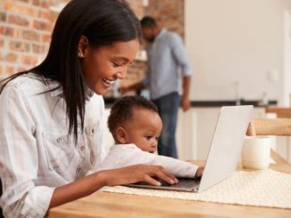 African American woman interacting with baby while studying at computer