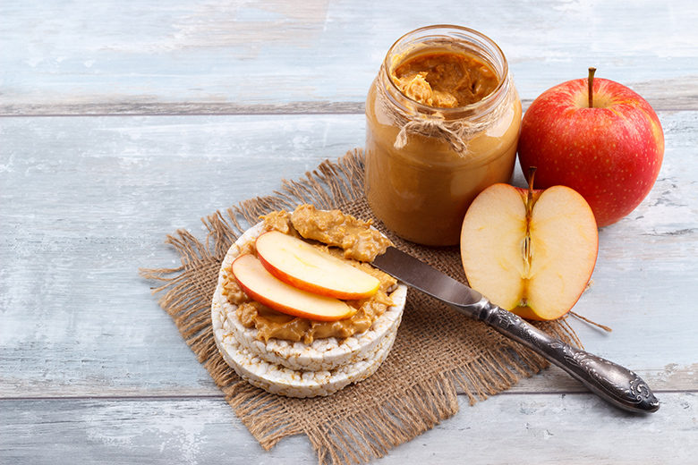 Breakfast with rice cakes, peanut butter and apple on old wooden background