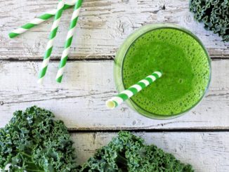 Green smoothie and fresh kale on a weathered wood background