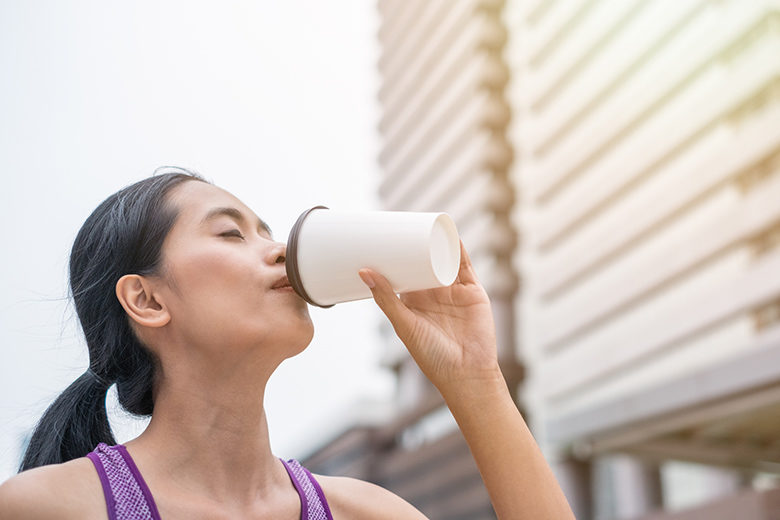 Woman drinking coffee after exercise is completed at urban