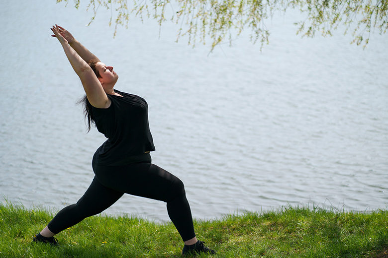 Woman doing yoga, relaxing near lake